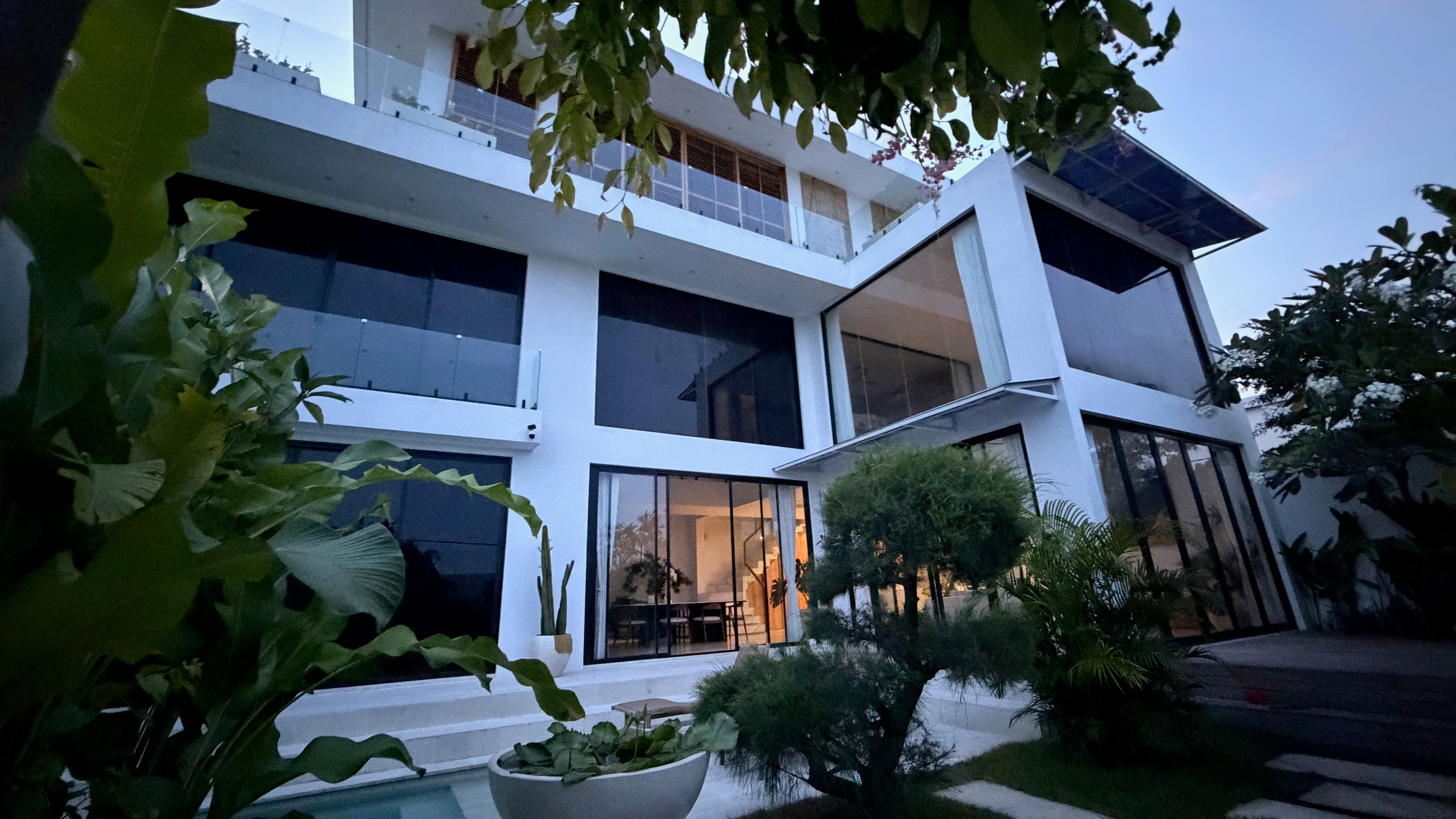 The white villa at The Summer Place at dusk — stacked volumes, lit glass and the plunge pool in the garden below.