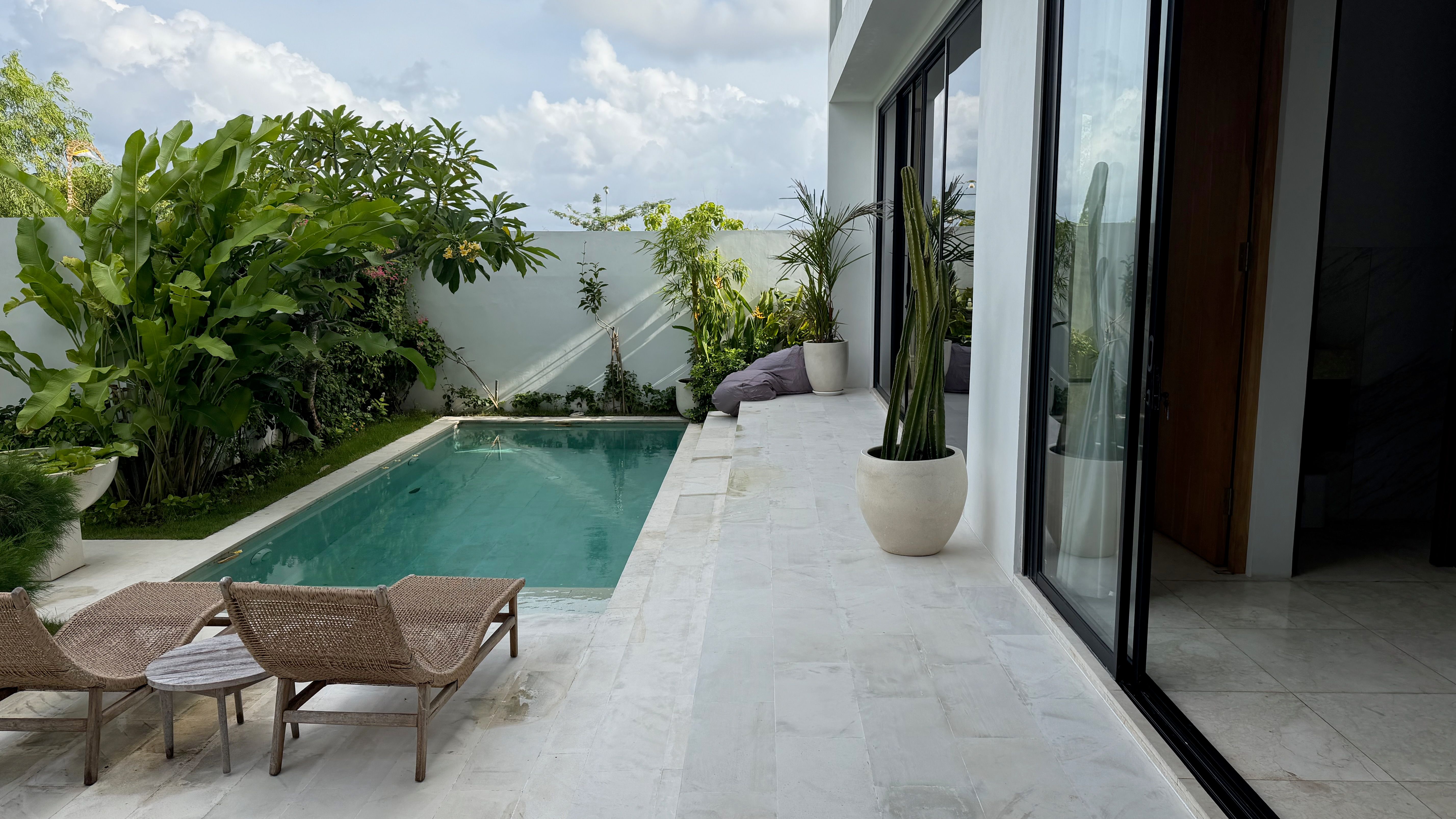 The plunge pool and marble deck with loungers, the white villa behind.