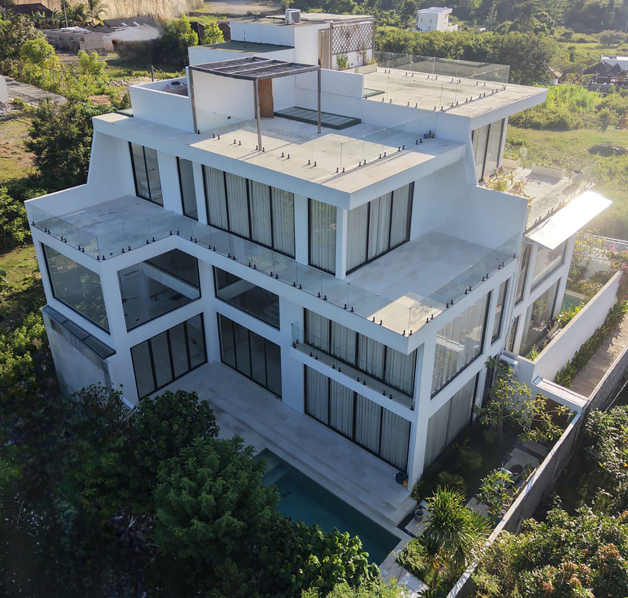 The villas seen from above — stacked white levels stepping down the ridge to the plunge pool.