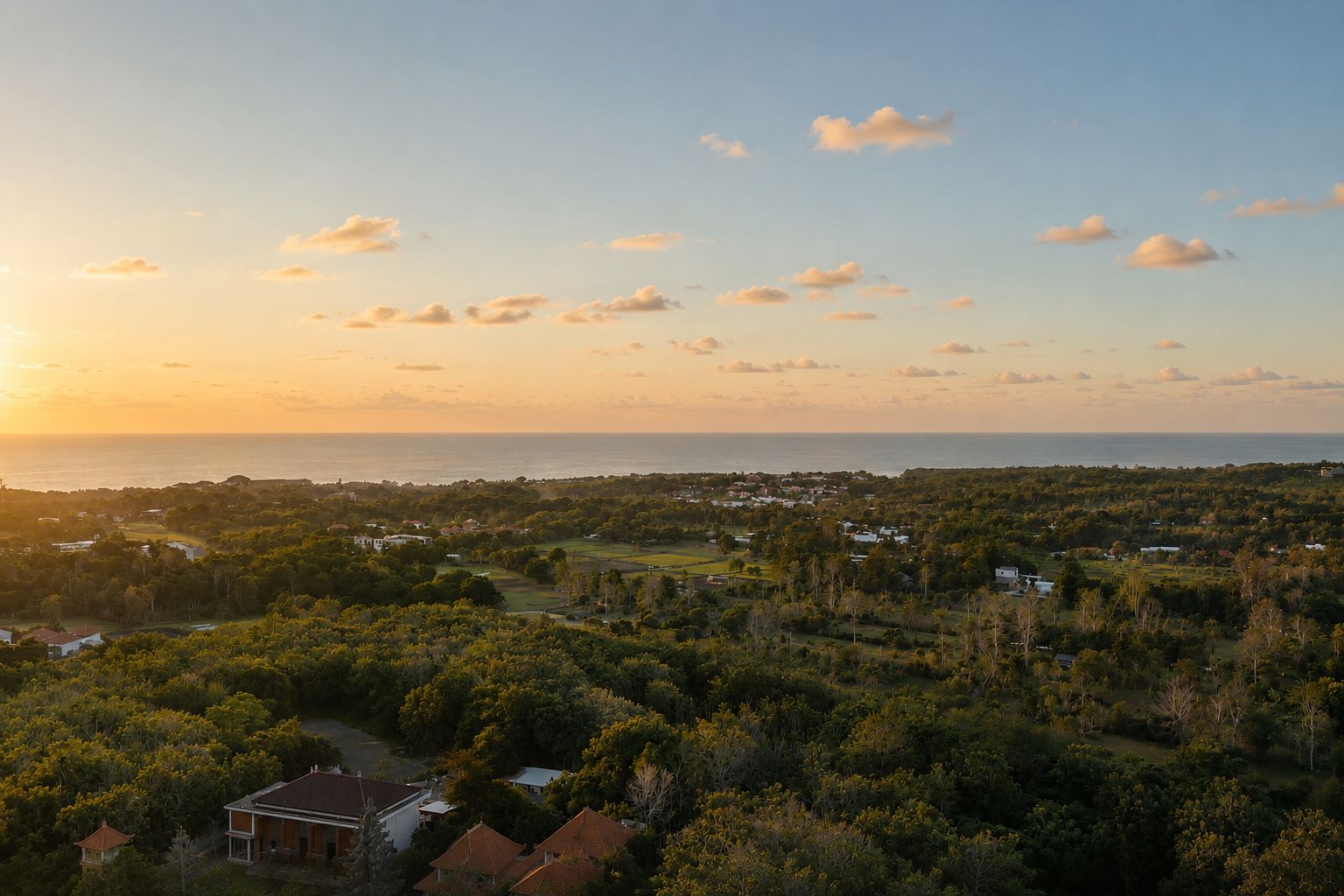 A band of sea on the far horizon at sunset, the Bukit jungle falling away below in warm golden light.