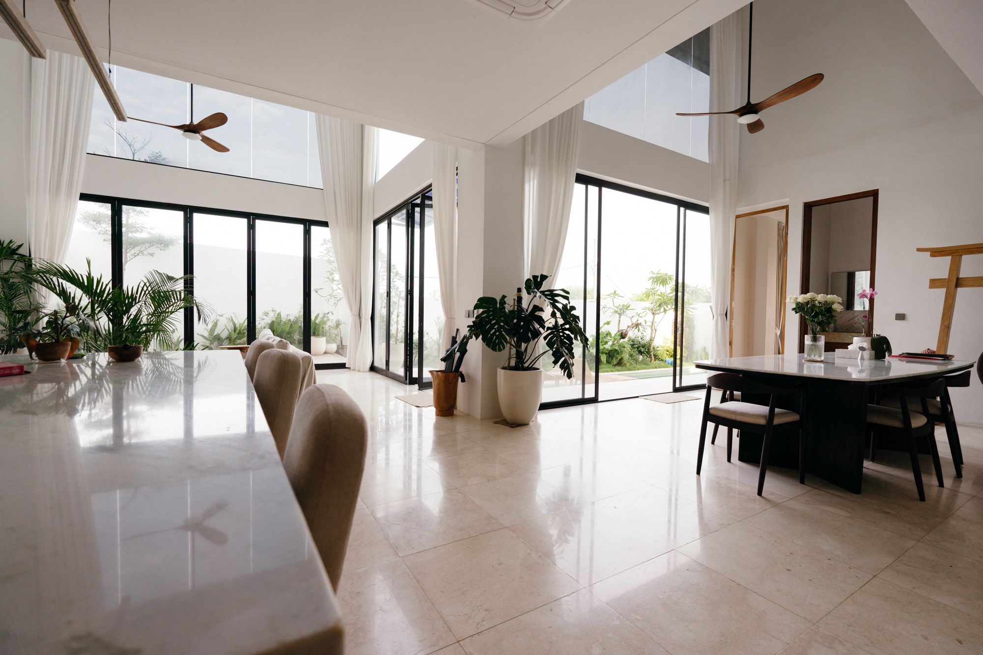 The living room where the glass sliders fold back to the marble deck and garden.