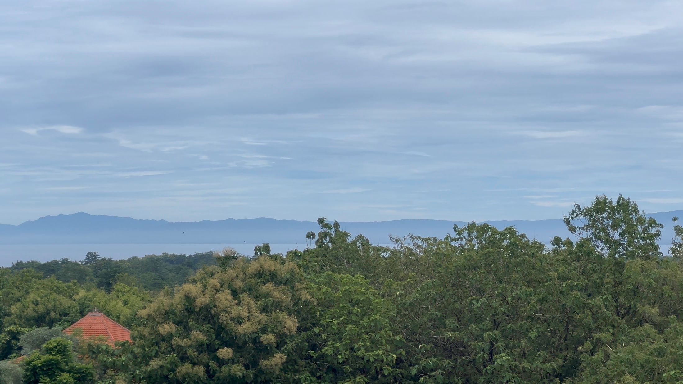 The terrace outlook: the green Bukit falling away to the mainland mountains on the hazy horizon.
