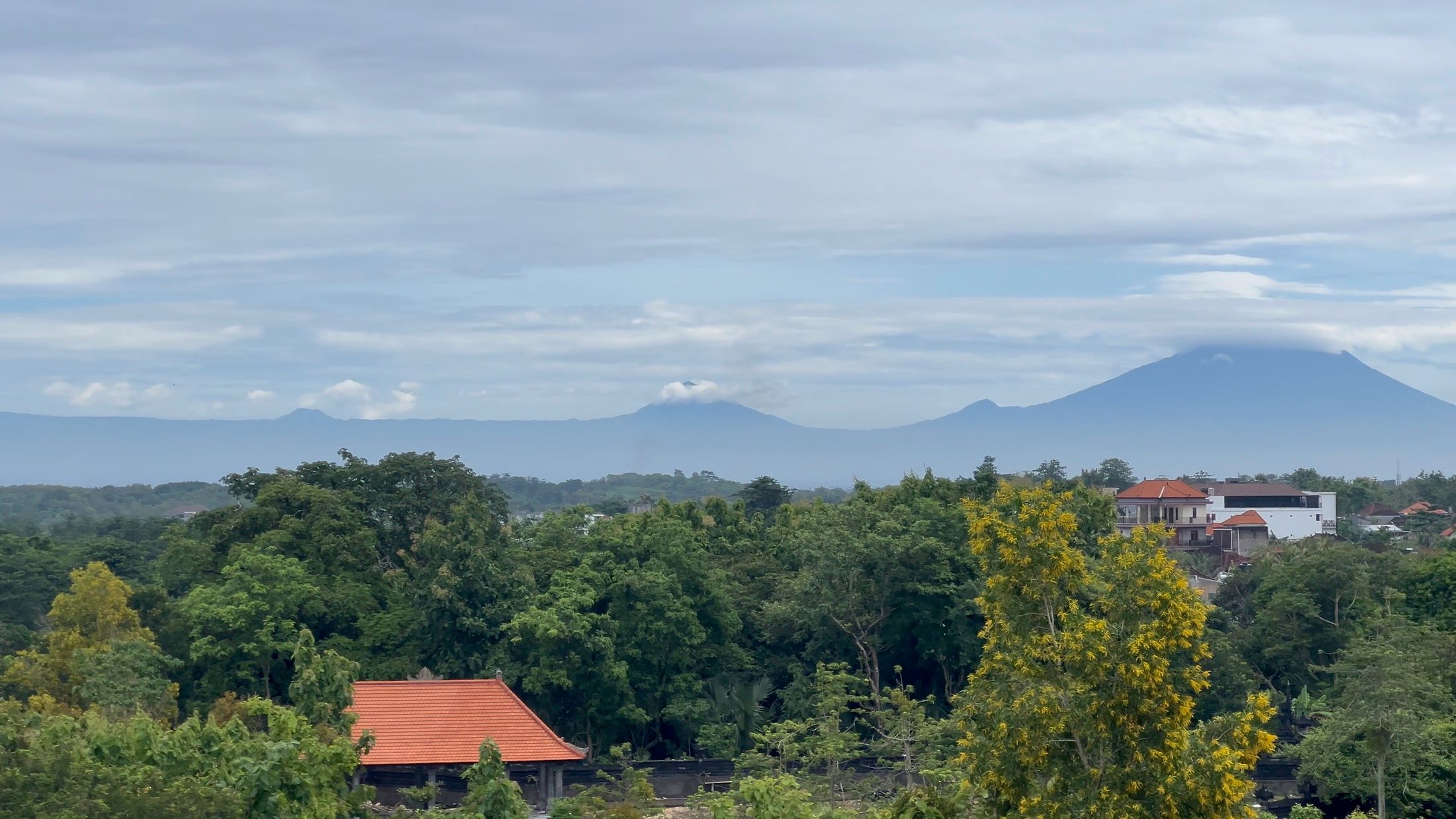 Further round: Gunung Agung standing over the trees and the distant rooftops.